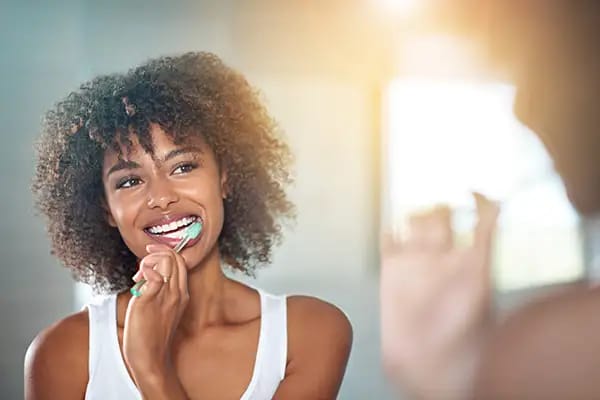 Woman brushing teeth to counteract dry mouth from allergy medications