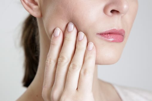 Person holding jaw in discomfort from toothache pain Person holding jaw in discomfort from toothache pain