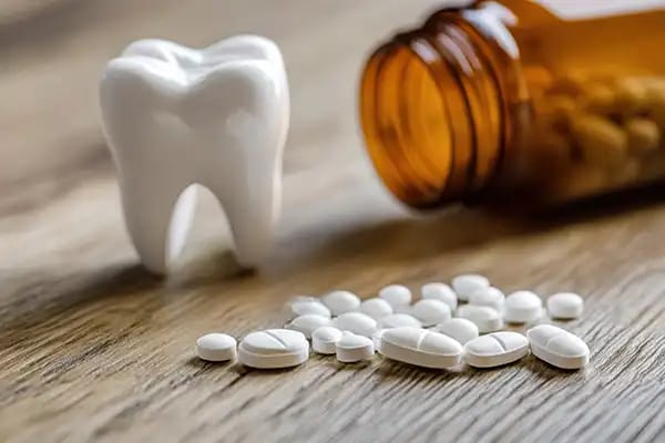 Pain relief medication next to tooth model for oral infection discomfort Pain relief medication next to tooth model for oral infection discomfort