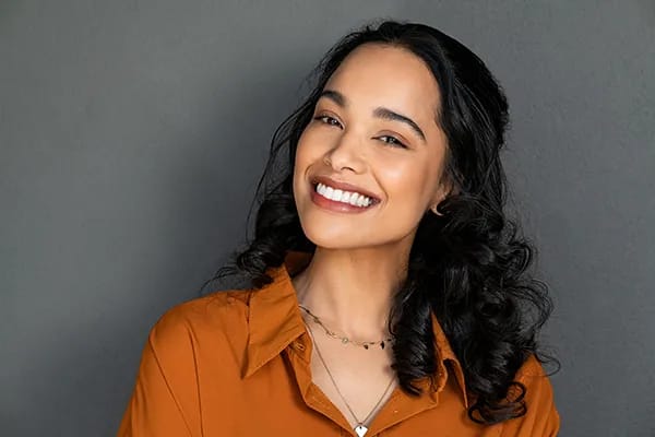 Woman showing off her improved smile after crown lengthening procedure