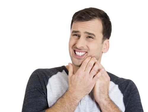 man holding face in pain because of mouth sores man holding face in pain because of mouth sores