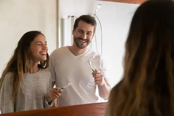 Couple brushing teeth together demonstrating proper tooth brushing technique Couple brushing teeth together demonstrating proper tooth brushing technique