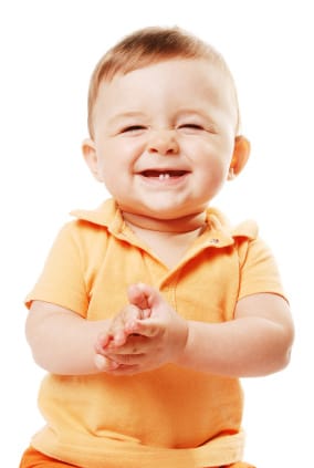 Smiling baby showing first erupting teeth highlighting early childhood dental care