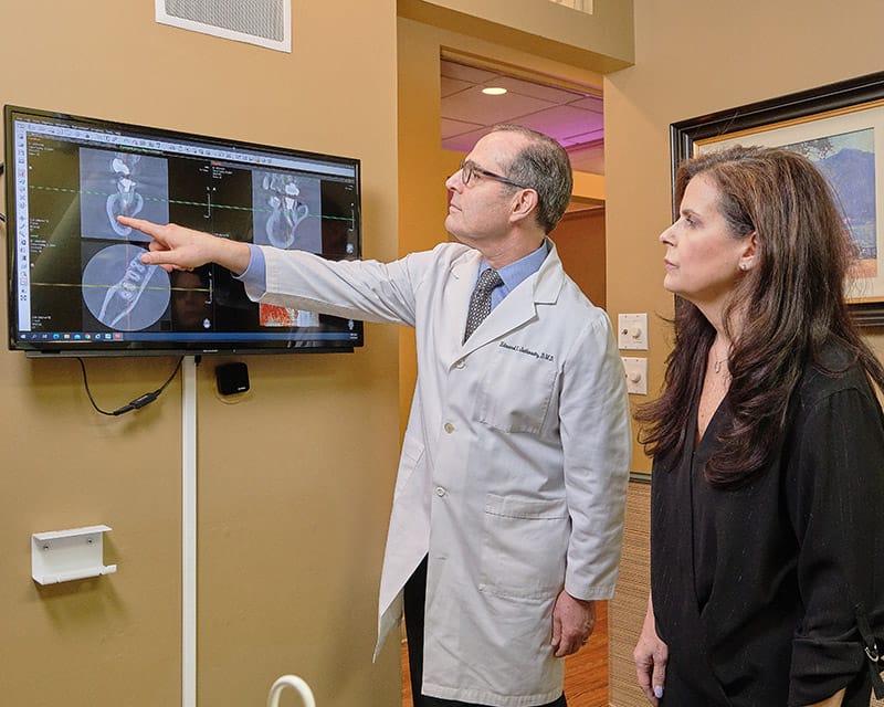 Dr. Jutkowitz explains gum treatment options to a female patient in Roslyn Heights.
