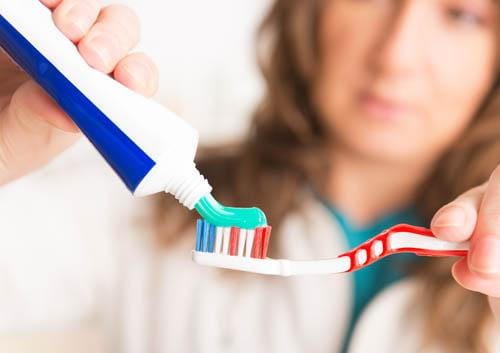 Woman adding toothpaste to toothebrush Woman adding toothpaste to toothebrush