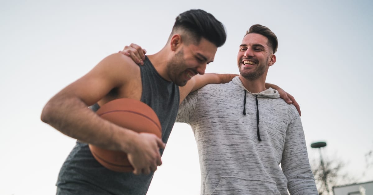 Two basketball players huddling while holding a basketball Two basketball players huddling while holding a basketball