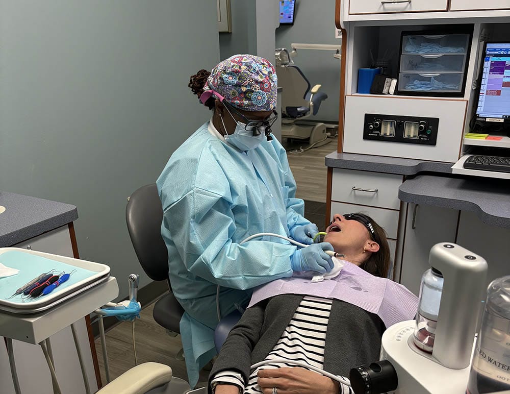 Female dental hygienist using GBT to clean a patient’s teeth in Marietta